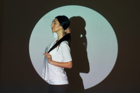 Circle and shadow. Beautiful young woman is in projector neon lights in the studio.