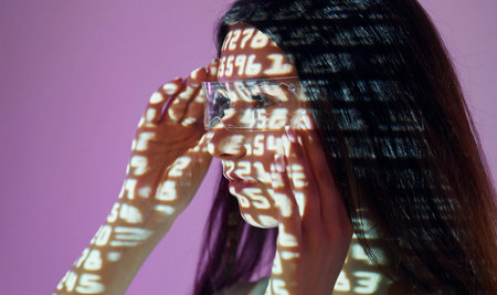 Different numbers. Beautiful young woman is in projector neon lights in the studio.