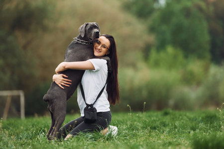 Embracing the pet. Young brunette is having a walk with her dog outdoors.