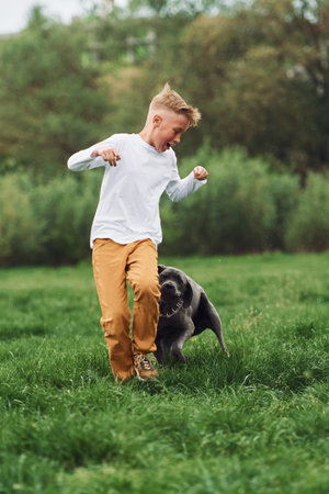 Running together. Little boy having fun at walk with his dog outdoors at summertime.