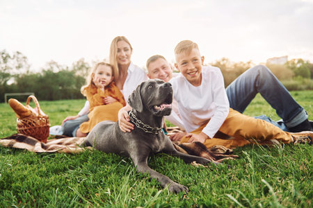 Laying down on the ground with dog. Family have weekend outdoors at summertime together.
