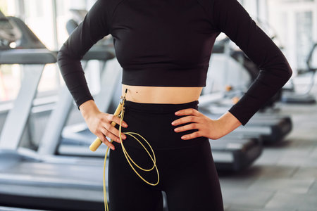 Close up view. Holding jump rope. Young beautiful woman in sportive clothes have fitness day in the...