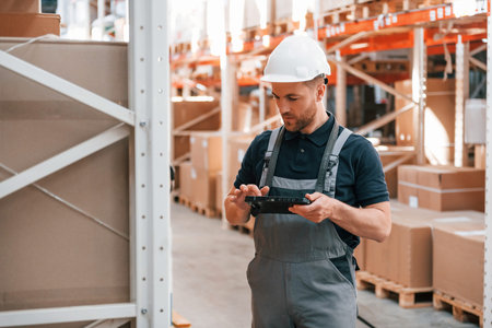 Checking data. Employee in uniform is working in the storage at daytime.