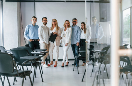 Standing and posing for a camera in the class. Group of professional business people is in the...