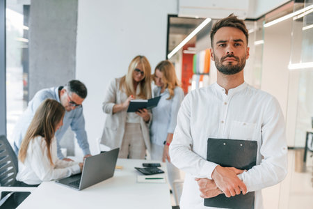 Beautiful cheerful man posing for the camera. Group of professional business people is in the...