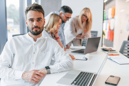 Young stylish man is working. Group of professional business people is in the office.