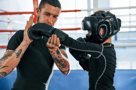 Practicing the punches. Coach is teaching the boy box techniques indoors.
