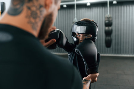 Practicing the punches. Coach is teaching the boy box techniques indoors.
