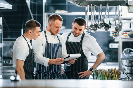 Looking at the documents. Kitchen workers is together preparing the food.
