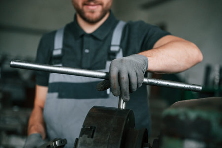 Focused on the developing the parts. Man in uniform is in workstation developing details of...
