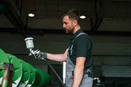 Painting details. Man in uniform is in workstation developing details of agriculture technique.