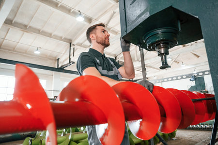 Professional engineer operating machine. Man in uniform is in workstation developing details of...