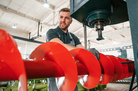 Attention to detail. Man in uniform is in workstation developing parts of agriculture technique.