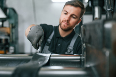 Clean parts. Man in uniform is in workstation developing details of agriculture technique.