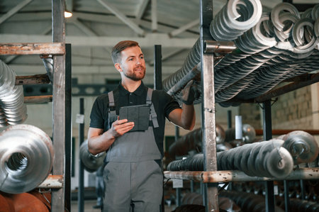 Holding tablet. Man in uniform is in workstation developing details of agriculture technique.