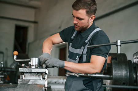 Focused on the developing the parts. Man in uniform is in workstation developing details of...