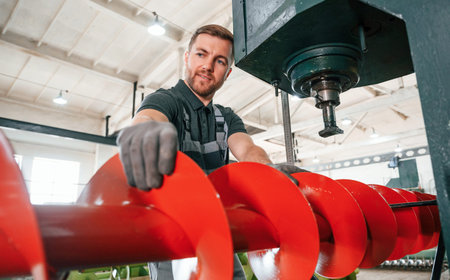 Attention to detail. Man in uniform is in workstation developing parts of agriculture technique.