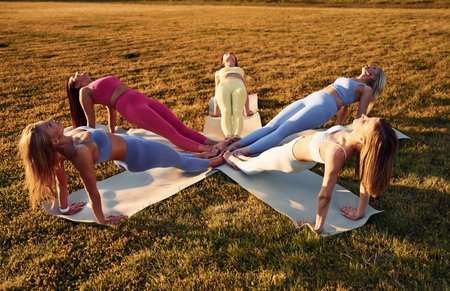 Doing upward plank. Group of women have fitness outdoors on the field together.
