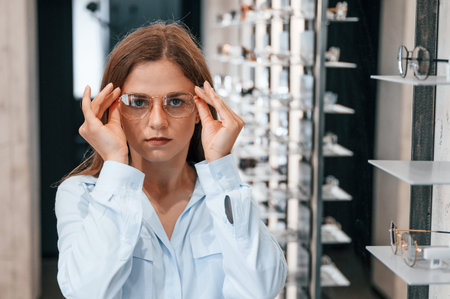 Portrait of woman that is with glasses in the store. Choosing right eyewear for correcting vision.