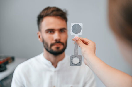 Holding tool. Man's vision checked by female doctor in the clinic by using special optometrist...