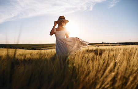 Nice landscape. Beautiful young bride in white dress is on the agricultural field at sunny day.の写真素材