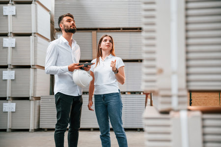 Young manager in formal clothes is working with woman in the warehouse.