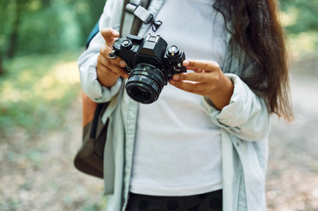 Using professional camera. Girl is in the forest at summer day time discovering new places.