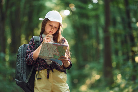 Using the map. Girl is in the forest at summer day time discovering new places.の写真素材