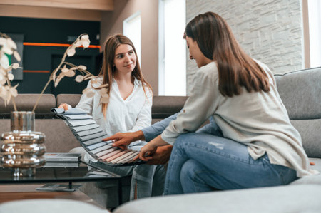 Sitting together. Woman helping couple with choosing the sofa and bed in the store.の写真素材