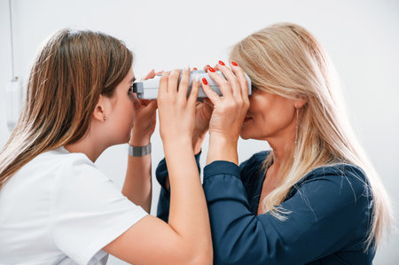 Woman's vision is tested by clinic worker that using special device.の写真素材