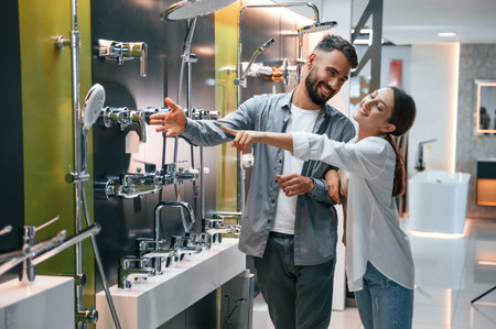 Having fun and looking for a bath cranes. Woman and man is in the store of goods for the home.