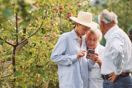 Woman showing something on the smartphone. Daughter is with her senior mother and father is in the...