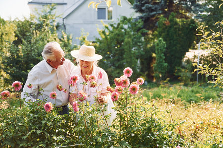 With beautiful flowers. Lovely senior couple is in the garden together.の写真素材