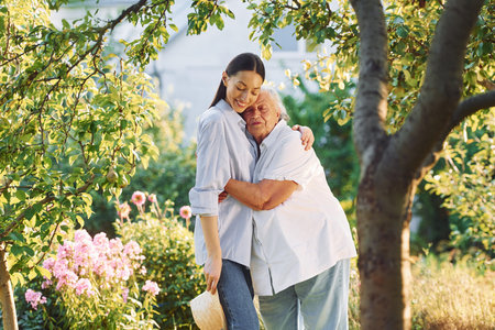 Time for a hugs. Young woman is with her senior mother is in the garden.の写真素材