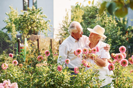 With beautiful flowers. Lovely senior couple is in the garden together.の写真素材
