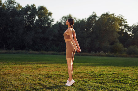 Flexible body. Young woman in yoga clothes is outdoors on the field.の写真素材