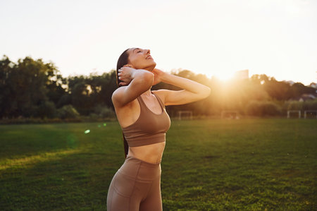 Against beautiful sunlight. Young woman in yoga clothes is outdoors on the field.の写真素材