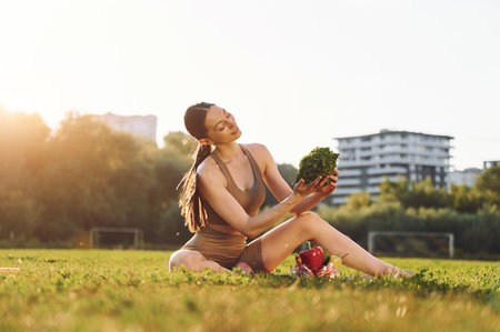 Conception of diet. Healthy food. Young woman in yoga clothes is outdoors on the field.の写真素材