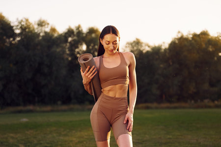 Standing against forest. Young woman in yoga clothes is outdoors on the field.の写真素材