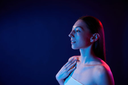 Side view. Portrait of young woman that is indoors in neon lighting.の写真素材