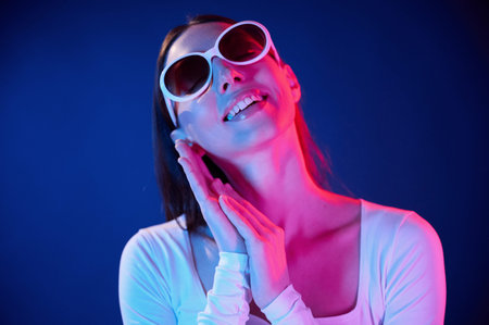 In sunglasses. Portrait of young woman that is indoors in neon lighting.