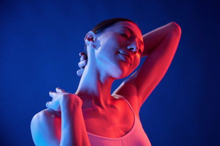 Happy and relaxed. Young woman in underwear is in the studio with neon lights.