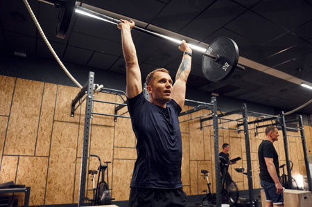 Exercises for the hands. Strong man is lifting barbell in the gym.