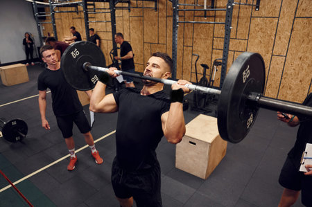 Exercises for the hands. Strong man is lifting barbell in the gym.