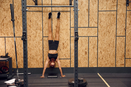 Strong woman doing push ups by standing upside down on the hands.