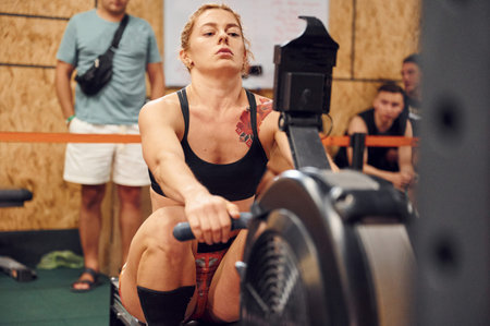 Exercises for the hands. Sportive woman doing exercises on rowing machine in the gym.