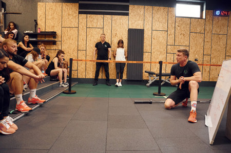 Ternopil, Ukraine - August 20, 2022: Sport master class indoors with many of people. Man is talking.