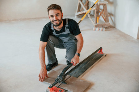 Tile cutting process. The man is making repairs in the apartment.
