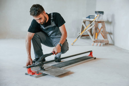 Tile cutting process. The man is making repairs in the apartment.