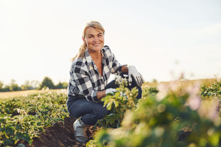 Sitting and smiling. Woman is on the agricultural field at daytime.